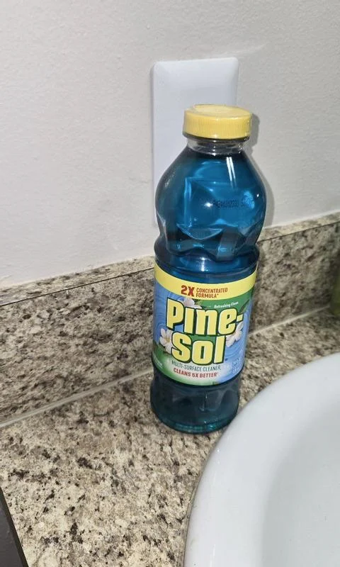 Bottle of Refreshing Clean Pine-Sol cleaner on granite bathroom counter next to porcelain sink.