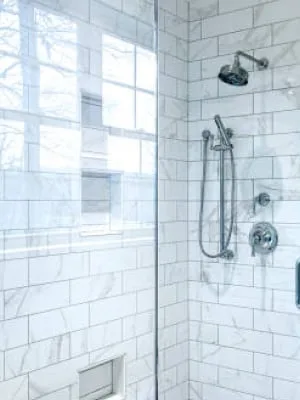 Ducha moderna con azulejos blancos y puerta de cristal