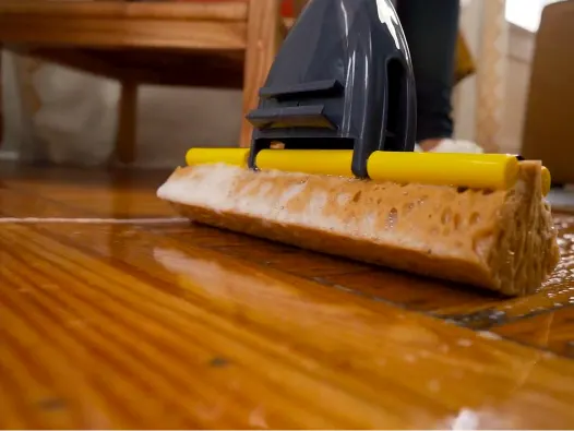 Trapeador de esponja amarillo limpiando piso de madera, vista cercana con esponja húmeda.