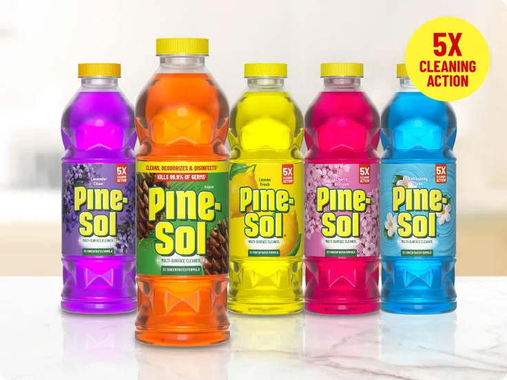 Bottles of Pine-Sol cleaner in 5 scents on white marble countertop, 5X cleaning action.