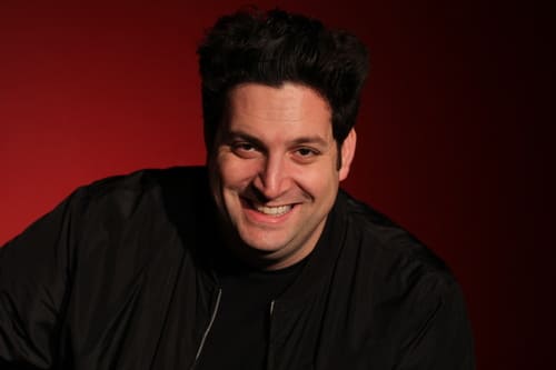 Portrait of smiling man with tall dark hair.