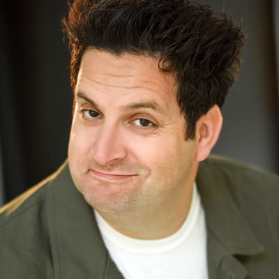 Man with dark tall hair smirking at the camera