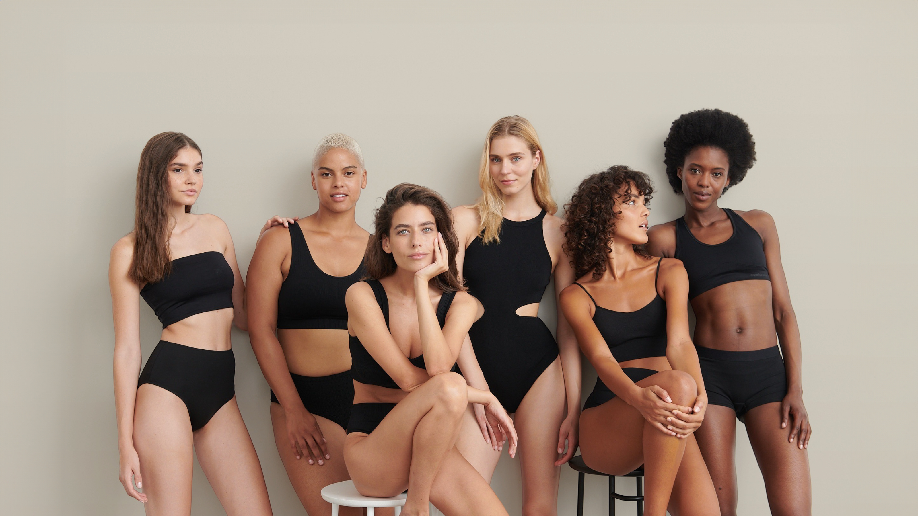 Grupp av 6 kvinnor i svarta sportiga bikinis som sitter och står.