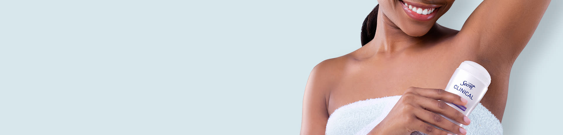 Smiling woman applying roll-on deodorant to her underarm.