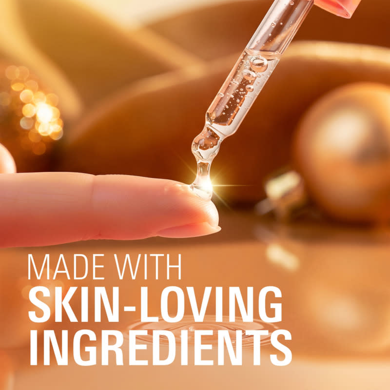 Dropper releasing serum onto a fingertip, emphasizing skin-loving ingredients with festive decorations in the background
