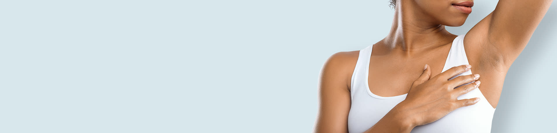 Woman applying deodorant to her underarm while wearing a white top.