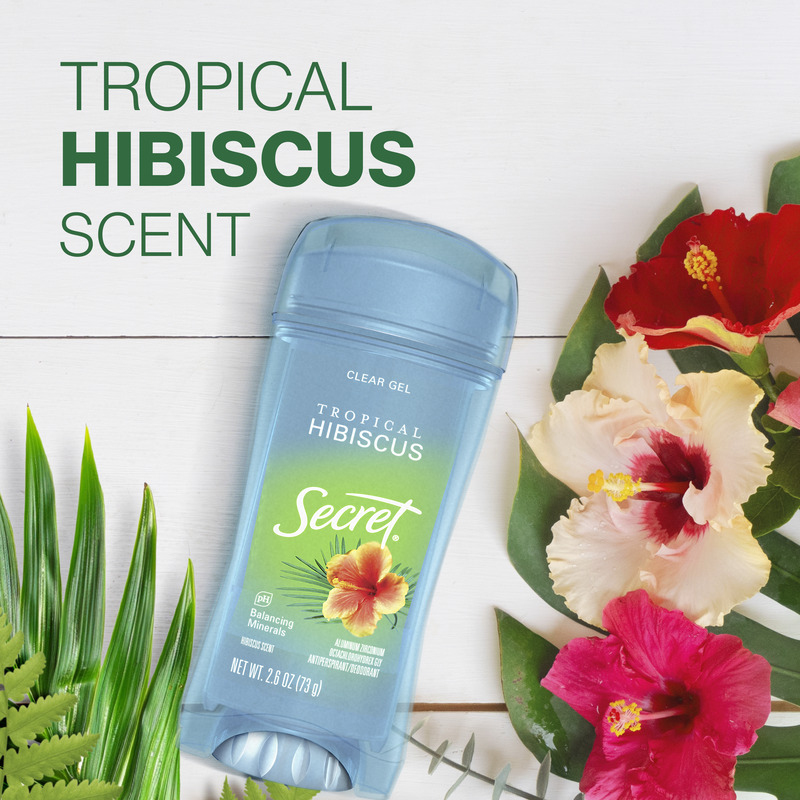 Secret clear gel deodorant bottle with tropical hibiscus scent surrounded by hibiscus flowers and green leaves on a white wooden background