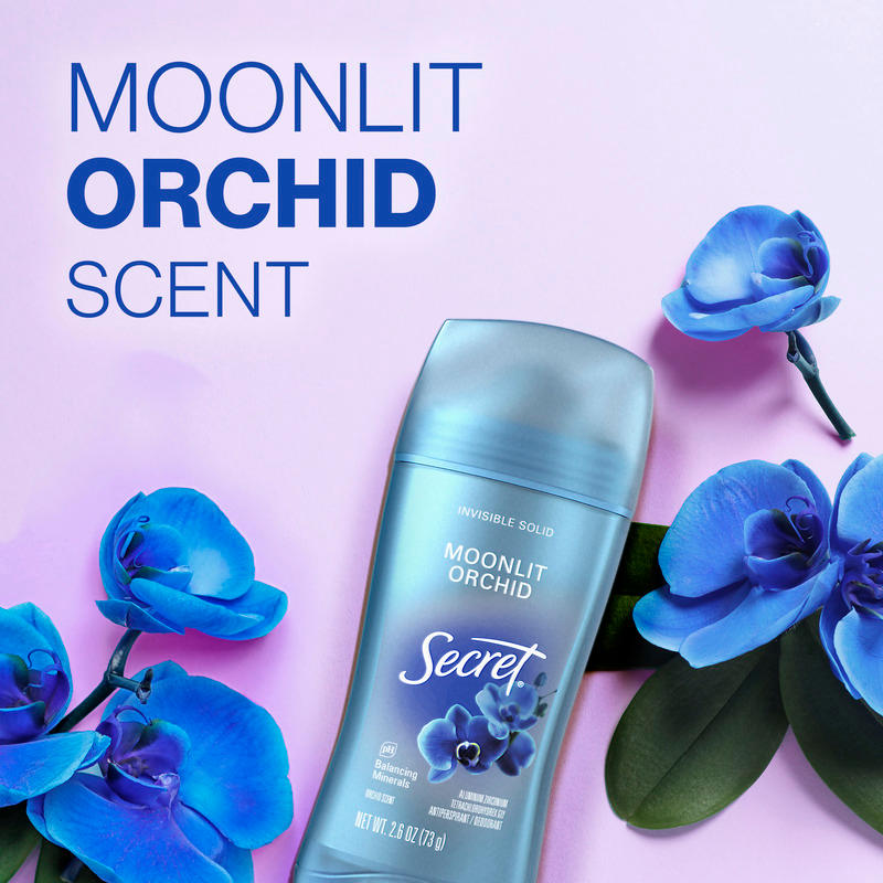 Secret deodorant stick with moonlit orchid scent surrounded by blue flowers against a soft purple background, emphasizing freshness and floral aroma