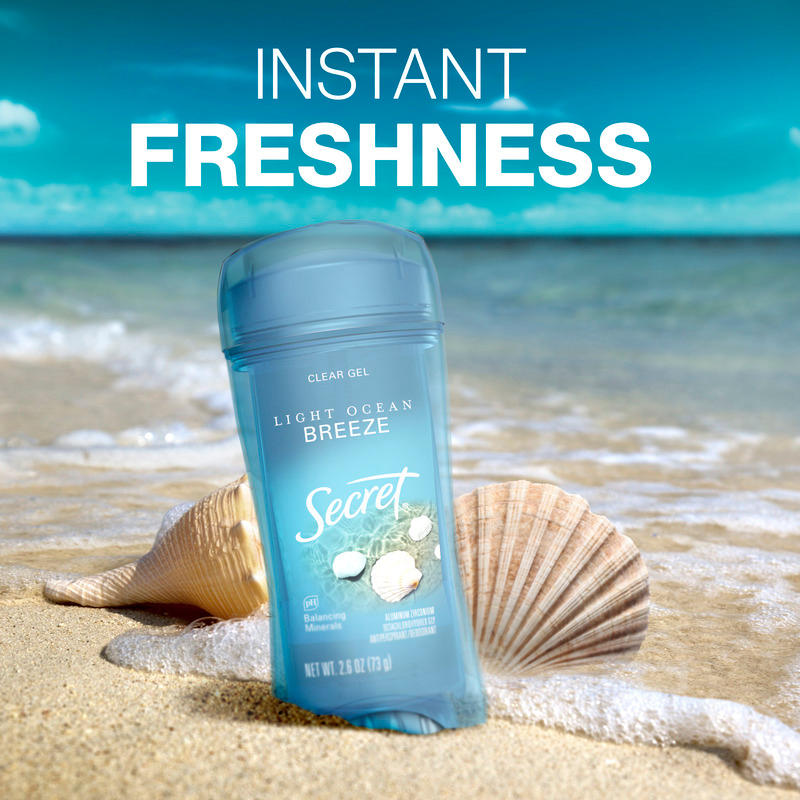 Secret clear gel deodorant in Light Ocean Breeze scent on a sandy beach with seashells, conveying a sense of instant freshness and relaxation