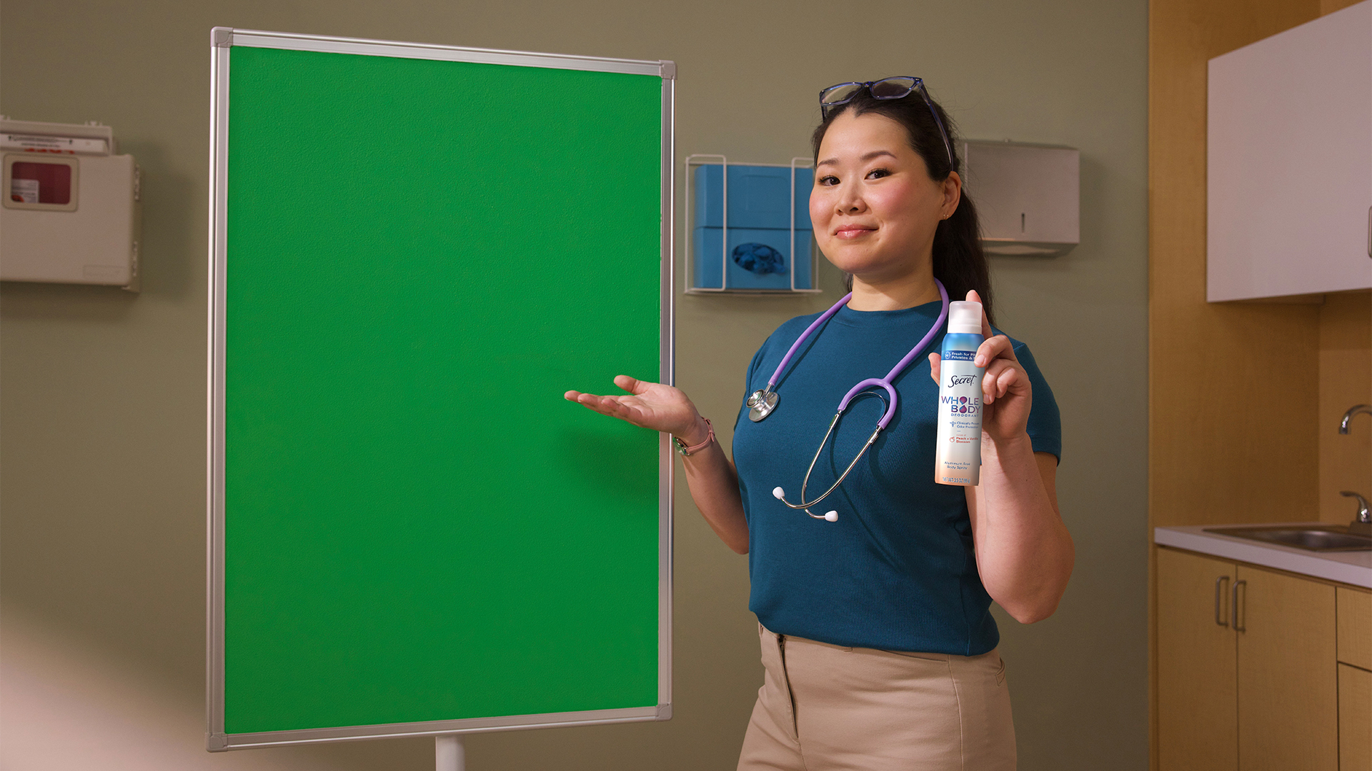 A woman standing in front of a green screen holding Secret Whole Body Spray can