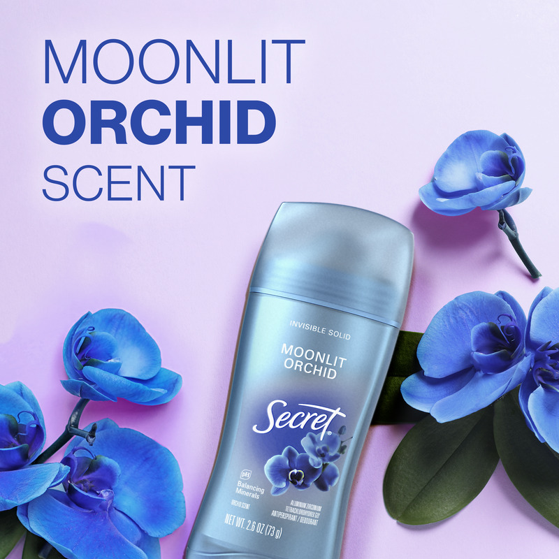 Secret deodorant stick with moonlit orchid scent surrounded by blue flowers against a soft purple background, emphasizing freshness and floral aroma