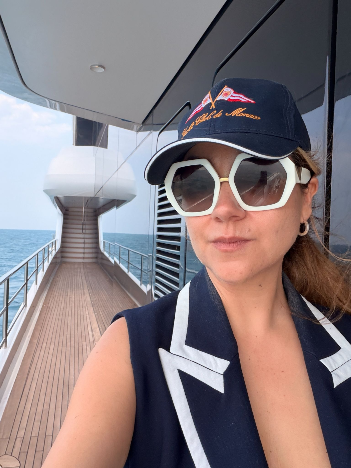 Marcela de Kern Royer in a Yacht Club de Monaco cap on the side deck of a superyacht at sea