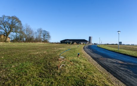 Udstykning af byggegrunde ved Ejersmindevej i landsbyen Skanderup. Udstykningen er en græsmark. Vejen ind i området ses i højre side af billede. Bagest ses et hus, der er under opførelse.