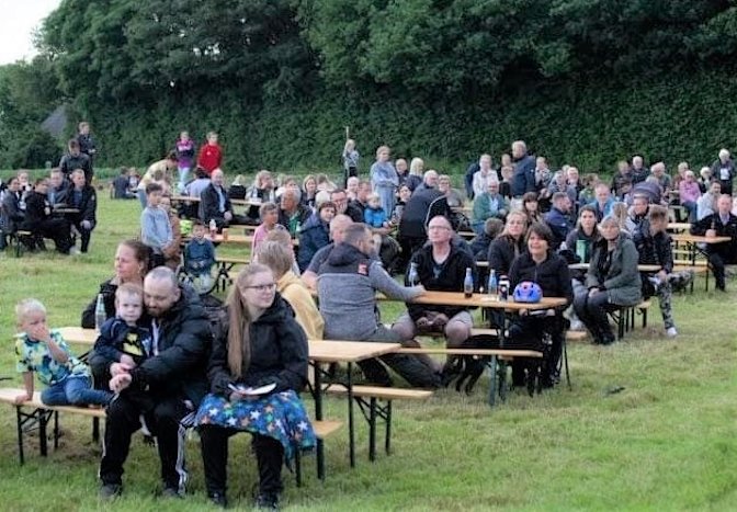 Sankthansfest i Viuf, hvor der deltog cirka 200 af byens borgere. De sidder ved borde på bænke og hygger sig sammen