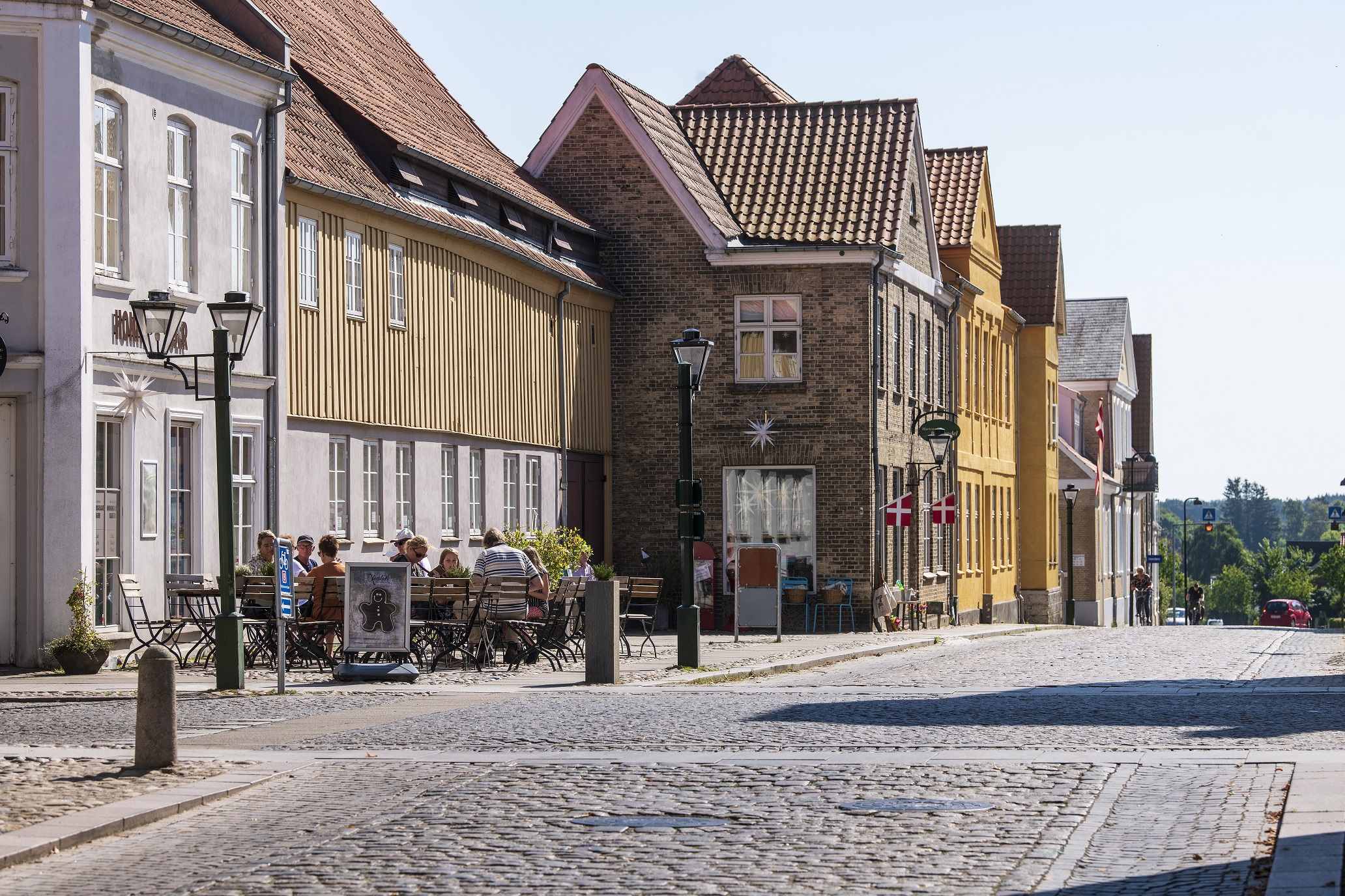 Et bybillede fra Christiansfeld med en brostensbelagt gade og en række karakteristiske huse i to til tre etager