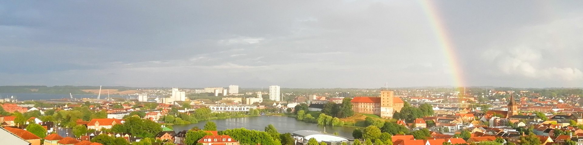 Udsigt over Kolding by fra Kikkenborgvej med Koldinghus og Slotssøen midt i billedet og med en dobbelt regnbue på himlen