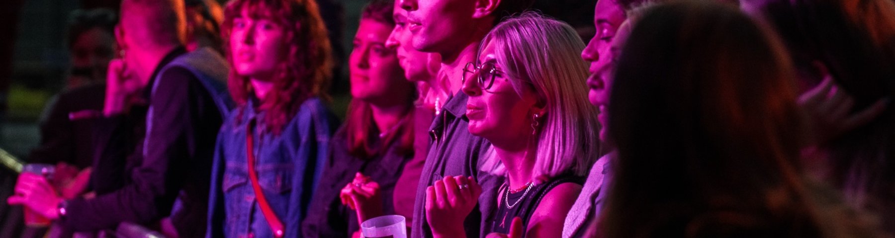 Publikum står ved scenekanten og lytter til musik