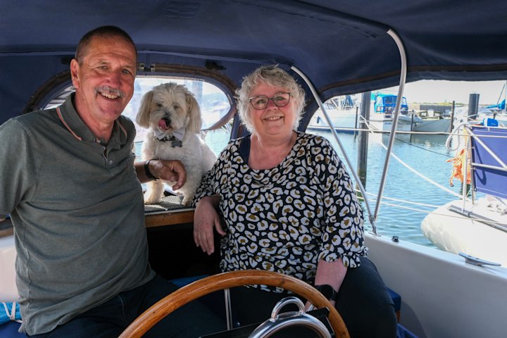 Jens Kristian og Kirsten sidder i cockpittet på deres båd med hunden Max bag sig i bagruden.