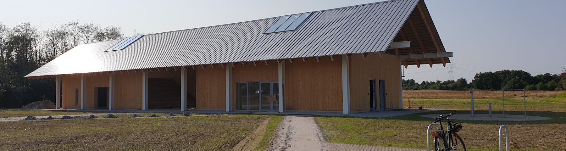 Det nyopførte Trailcenter Hylkedalen i solskin med en cykel parkeret udenfor