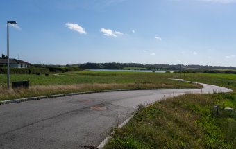 Udstykning med byggegrunde i Ødis, hvor vejen snor sig gennem området, og med Ødis Sø i baggrunden