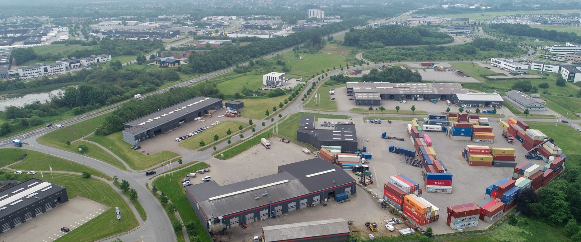 Dronefoto over erhvervsområde i Kolding Nord med virksomheder og en plads med farvestrålende containere i gule, blå, røde og orange farver