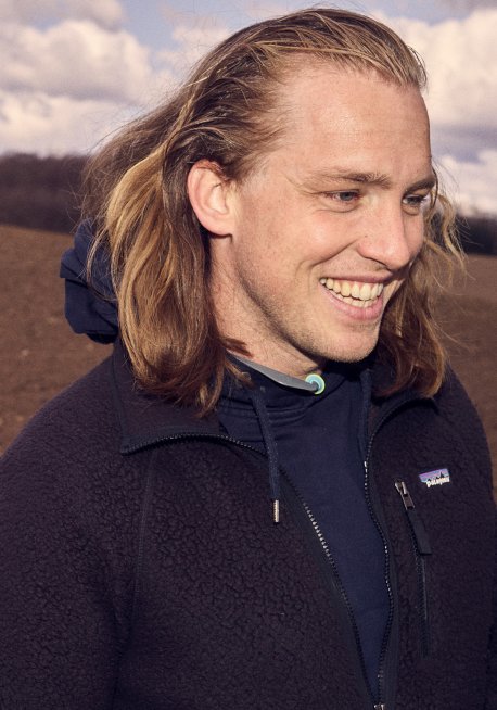 Nærbillede af Philip Hulgaard, der står på en harvet, brun mark og smiler