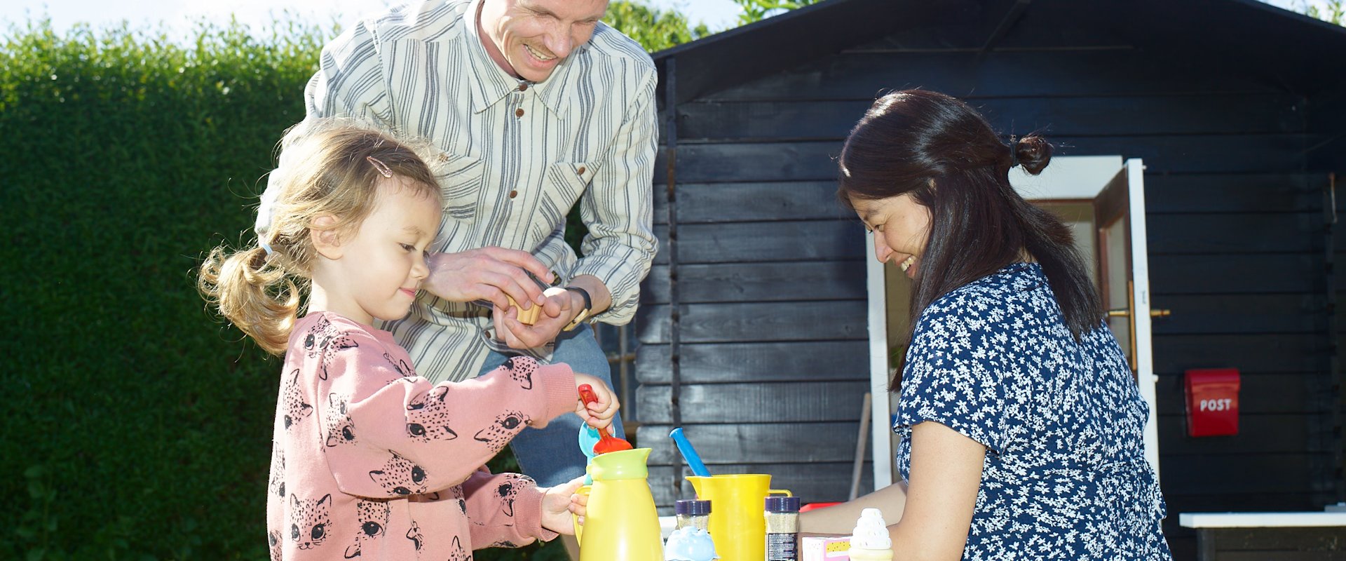 Sanne og Niels Kallesøe leger med deres datter ved legehuset i deres have