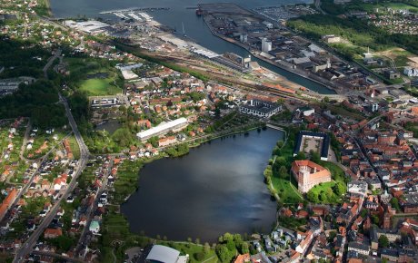 Kolding set fra oven med Koldinghus og Slotssøen lidt under midt i billedet og fjord og haven øverst i billedet.