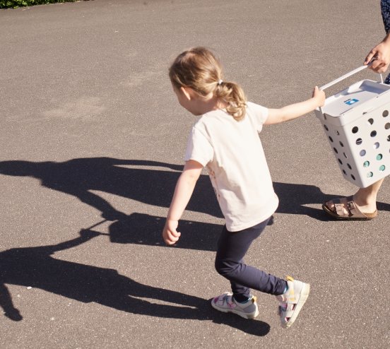Sanne Kallesøe bærer en fuld affaldsspand hen til affaldscontainerne sammen med sin datter