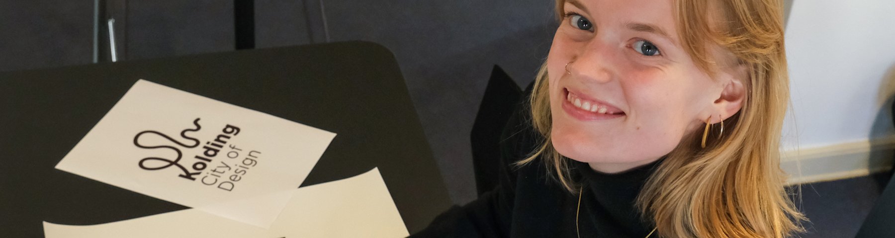 Nina Gantriis-Møller tegner. Ved siden af tegnepapiret ligger et print af designbyen Koldings nye logo, som Nina har skabt.