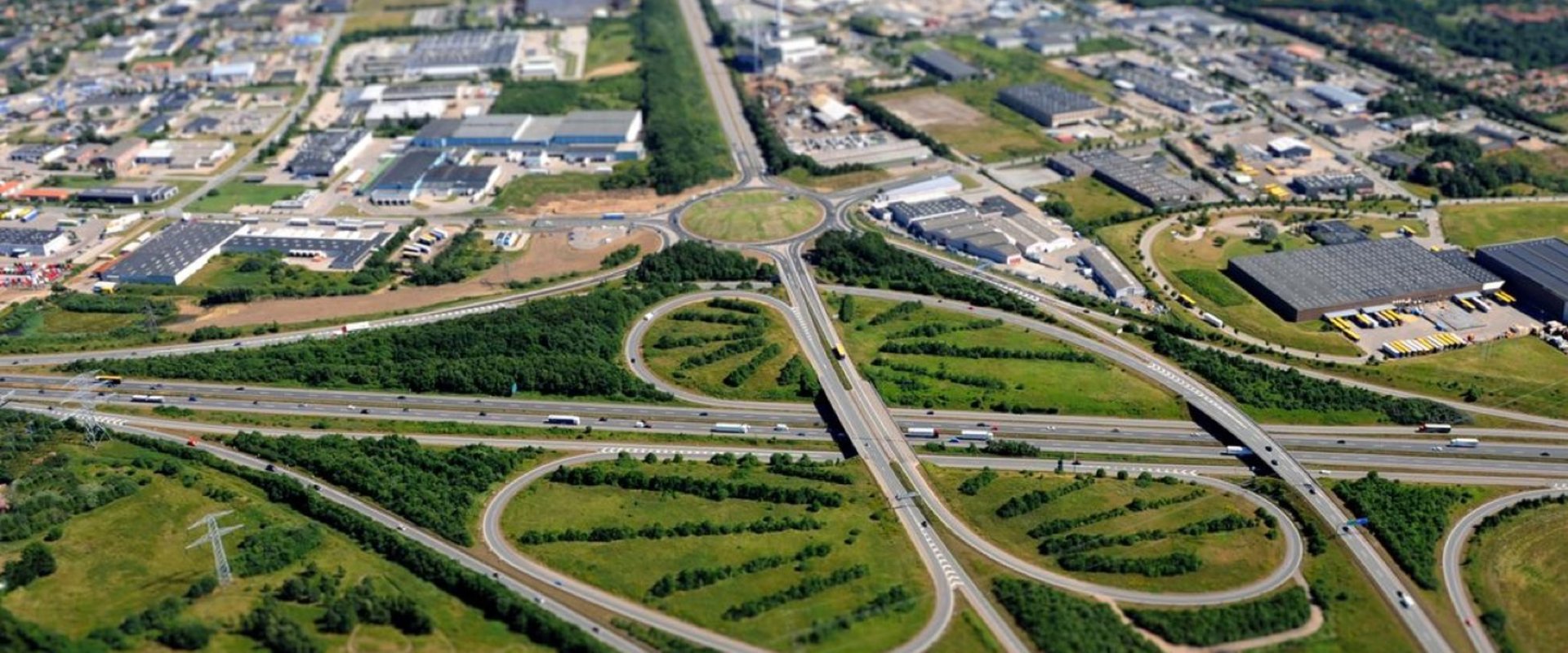 Dronefoto af motorvejskryds ved Kolding forrest i billedet med det tilgrænsende industriområde bagest i billedet