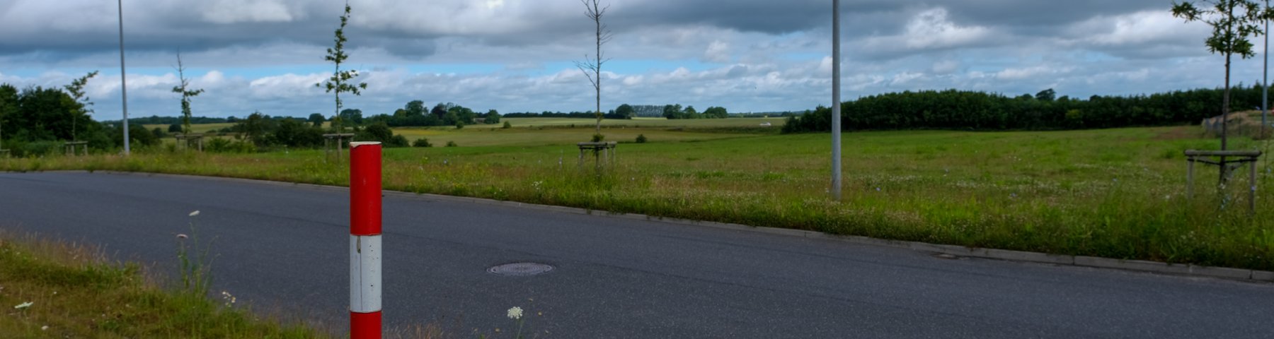 Udstykning af erhvervsjord ved Venusvej i Kolding Nord. Udstykningen består af grønne marker - en enkelt skelpæl ses i forgrunden og en vej skærer sig gennem området