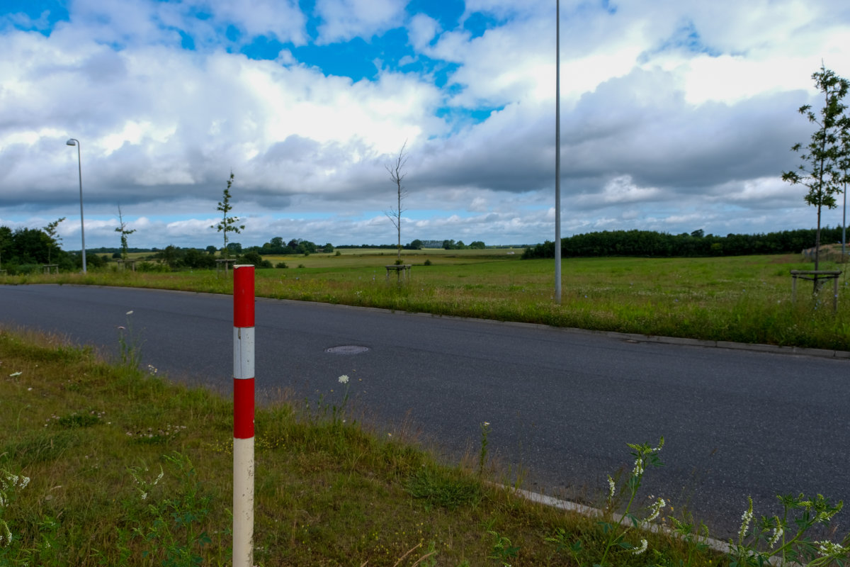 Udstykning af erhvervsjord ved Venusvej i Kolding Nord. Udstykningen består af grønne marker - en enkelt skelpæl ses i forgrunden og en vej skærer sig gennem området