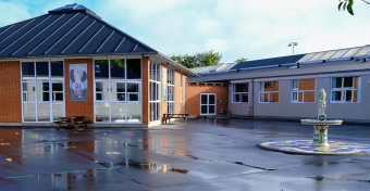 Fynslund Skole og Børnehus set fra skolegården. En vandfontæne er placeret i højre side af billedet