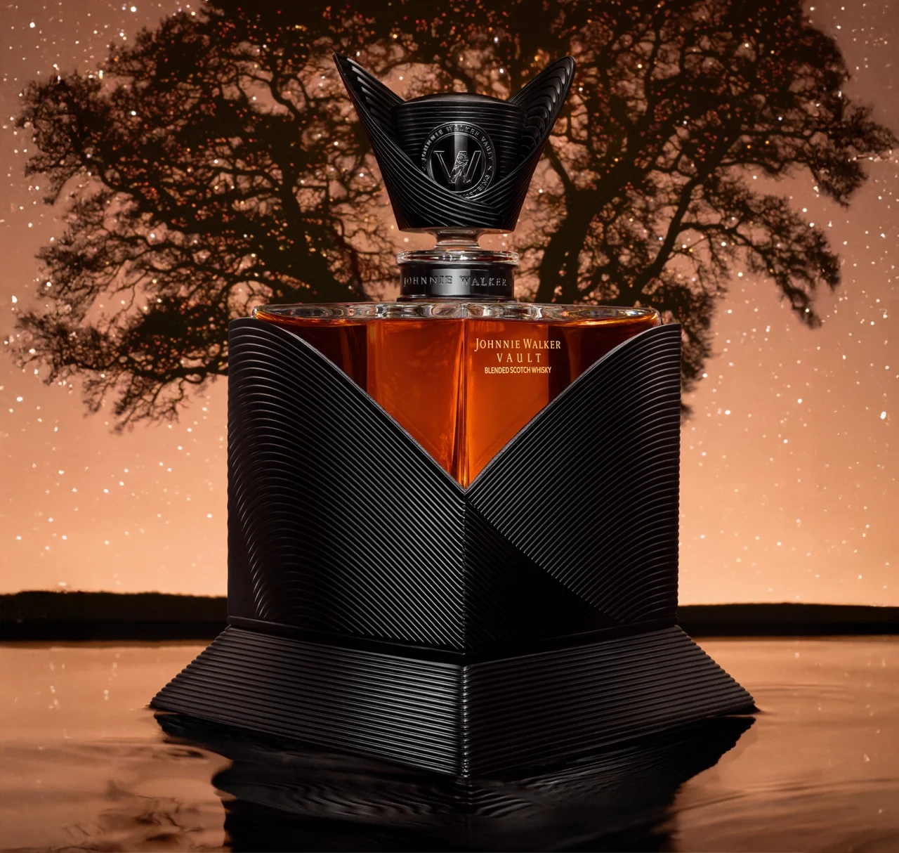 A luxurious Johnnie Walker whisky bottle with a unique black geometric design, set against a starry night sky and the silhouette of a large tree, reflected on a glossy surface.