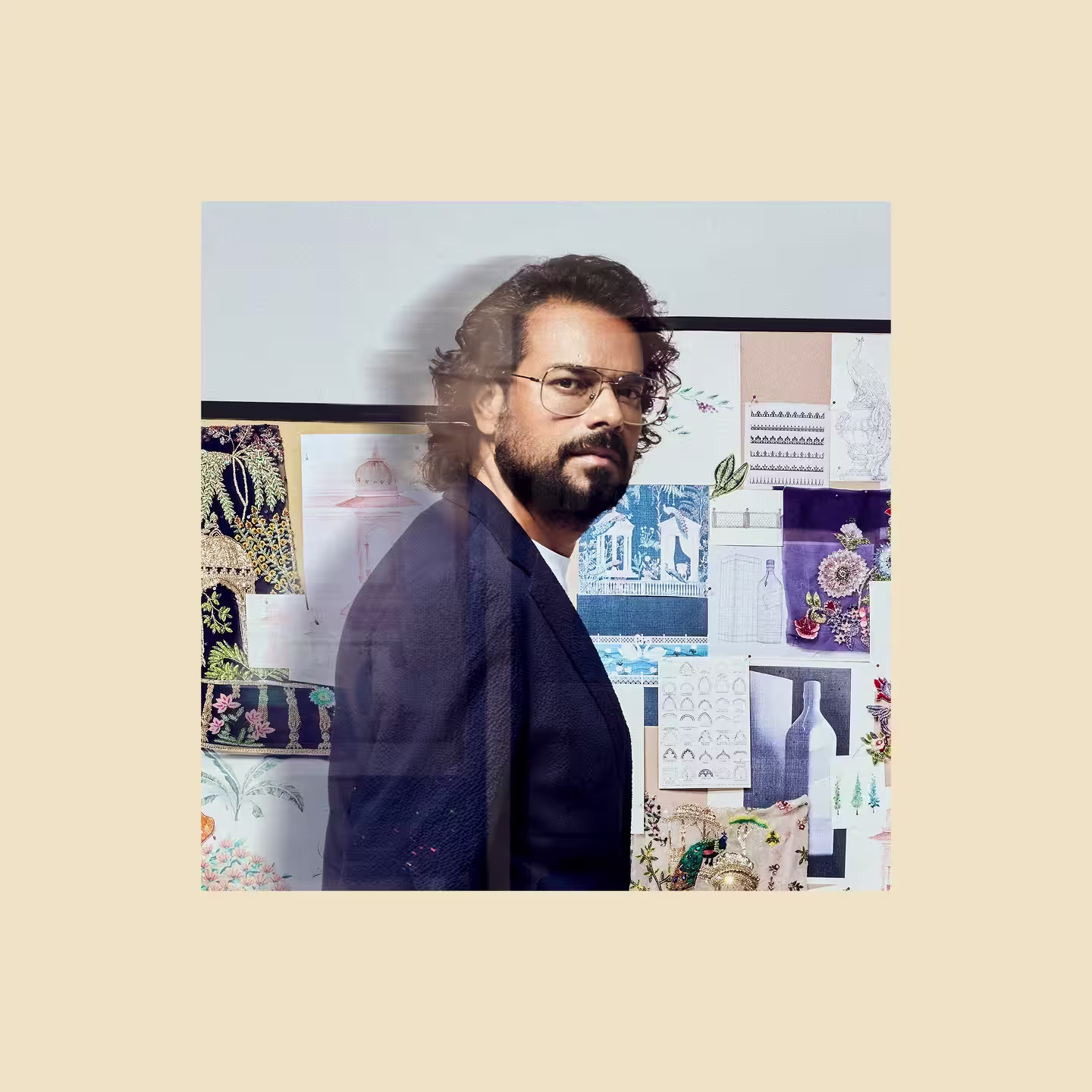 Black and white portrait of a Rahul Mishra with long hair wearing glasses, a dark blazer, and a smartwatch, standing with one hand on his chest against a plain background.