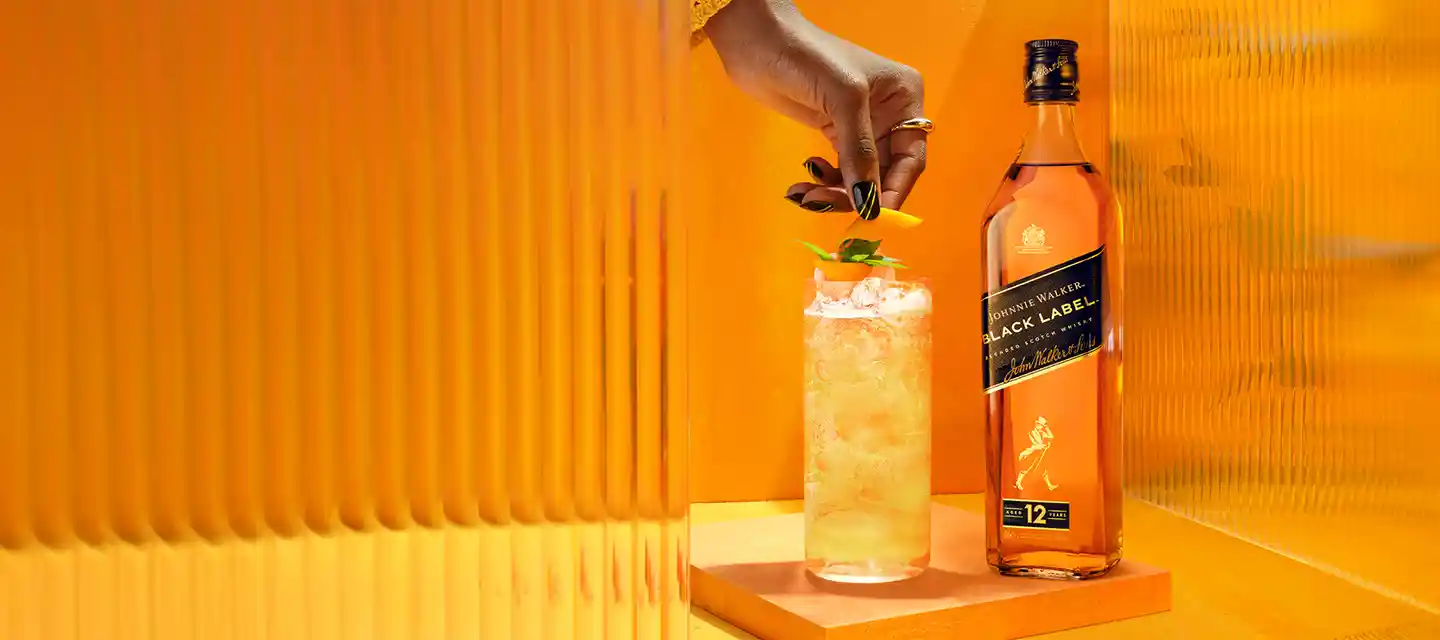 Oranje achtergrond met een Johnnie Walker zwarte fles en cocktails