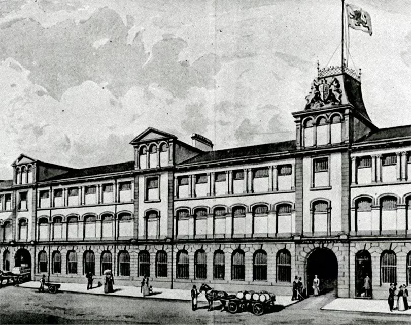A historic illustration depicting a grand building with ornate details, likely a factory or warehouse from the industrial era.