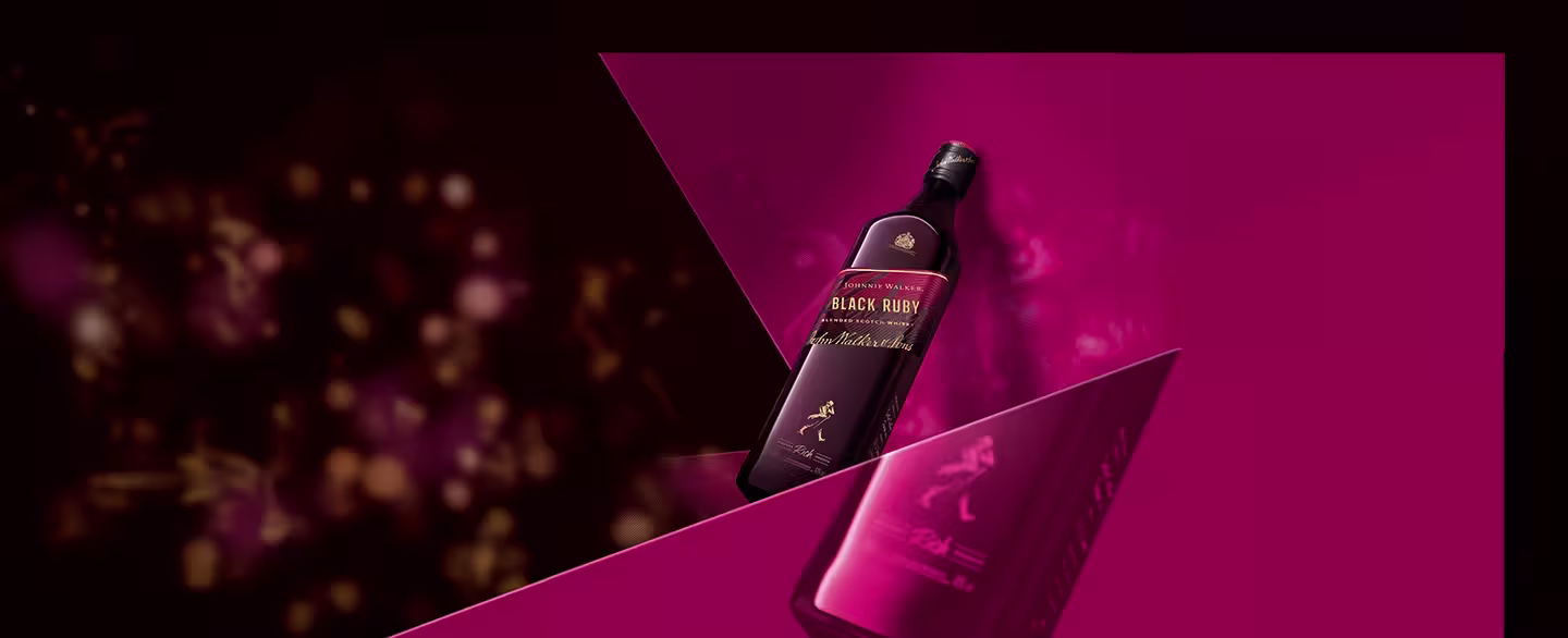 Bottle of Black Ruby whiskey with a maroon label, positioned diagonally against a maroon and pink geometric background. The background features bokeh light effects, creating a luxurious and sophisticated ambiance.