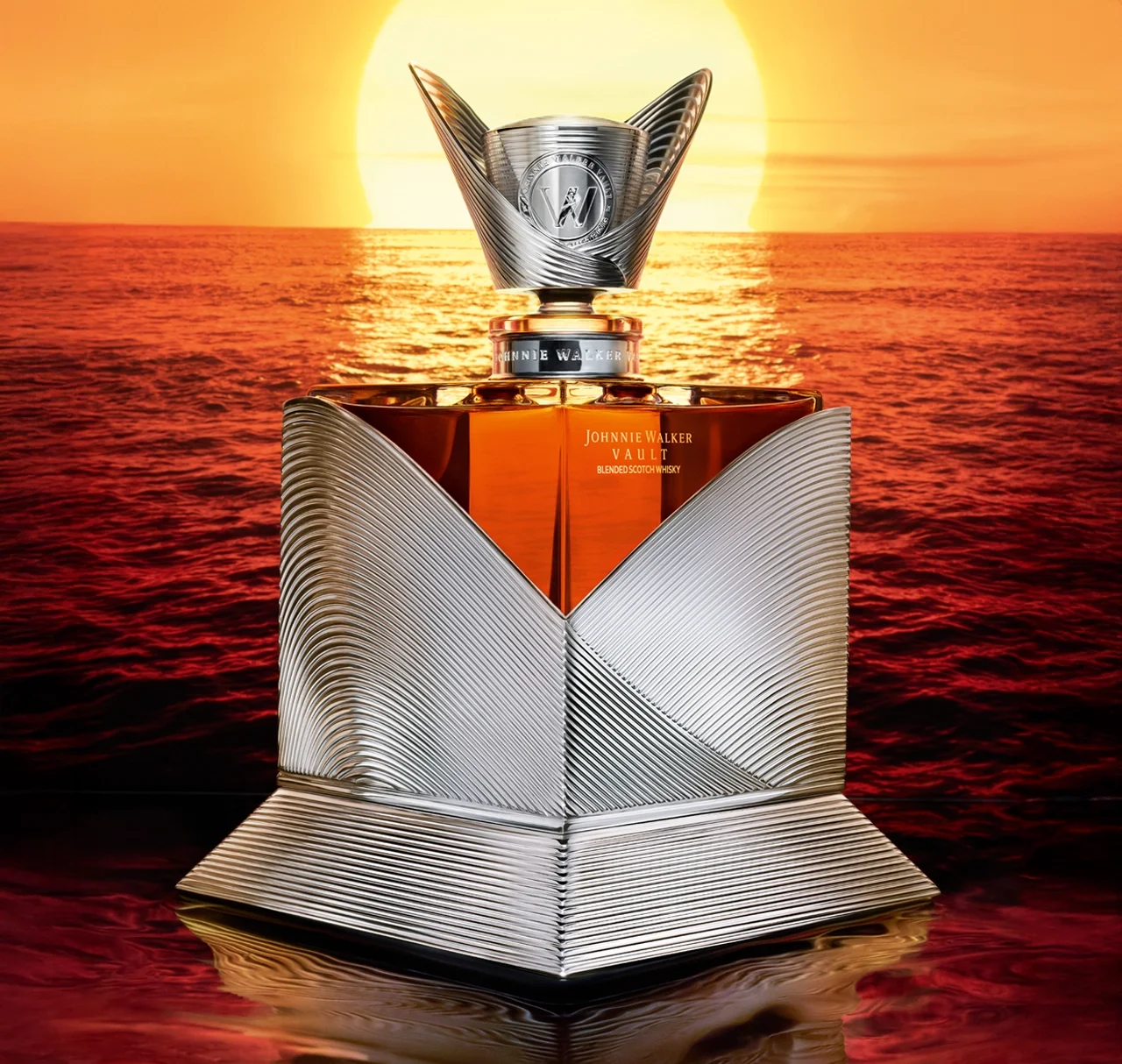 A luxurious silver and glass bottle of Johnnie Walker whisky stands in front of a vibrant sunset over the ocean, with the golden sun reflecting on the water and the bottle’s metallic design catching the light.