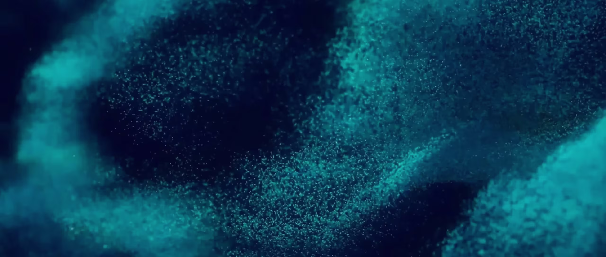 Abstract blue particles clustered on a dark background, creating a textured, nebula-like effect.