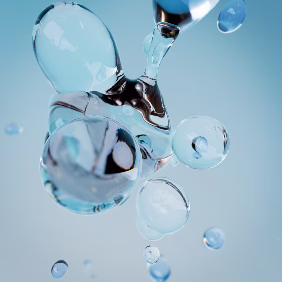Close-up of transparent water droplets merging and floating against a soft blue background, with light reflections creating a fluid and abstract appearance.