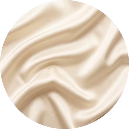 Close-up van een gladde, ivoorkleurige zijden stof met zachte, vloeiende plooien en een soepele, glanzende textuur.