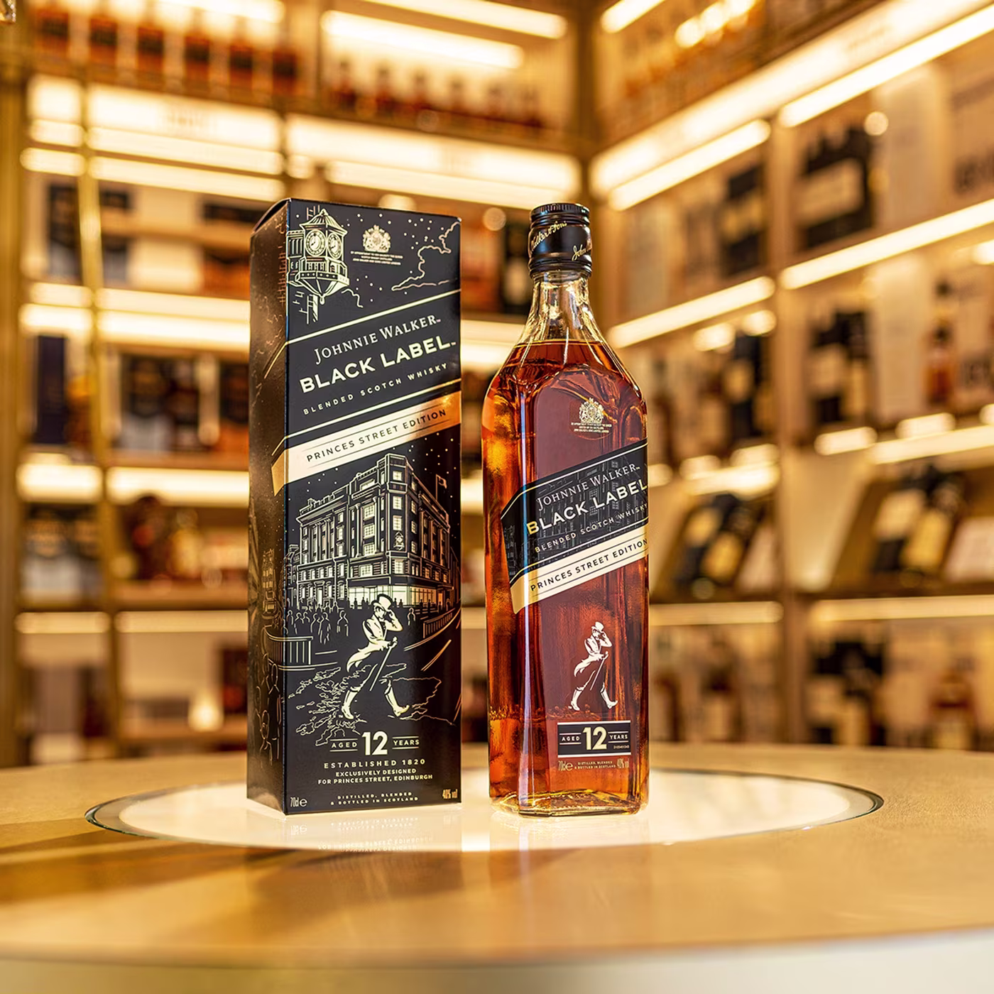 A bottle and box of Johnnie Walker Black Label 12 Year Old whisky displayed on a round, lit table in a liquor store.