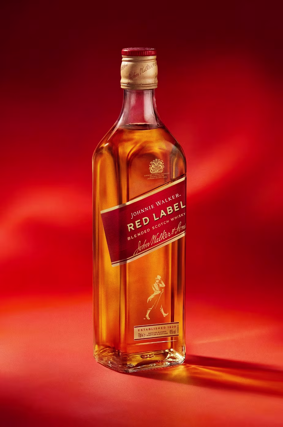 A bottle of Johnnie Walker Red Label whisky on a vibrant red background.