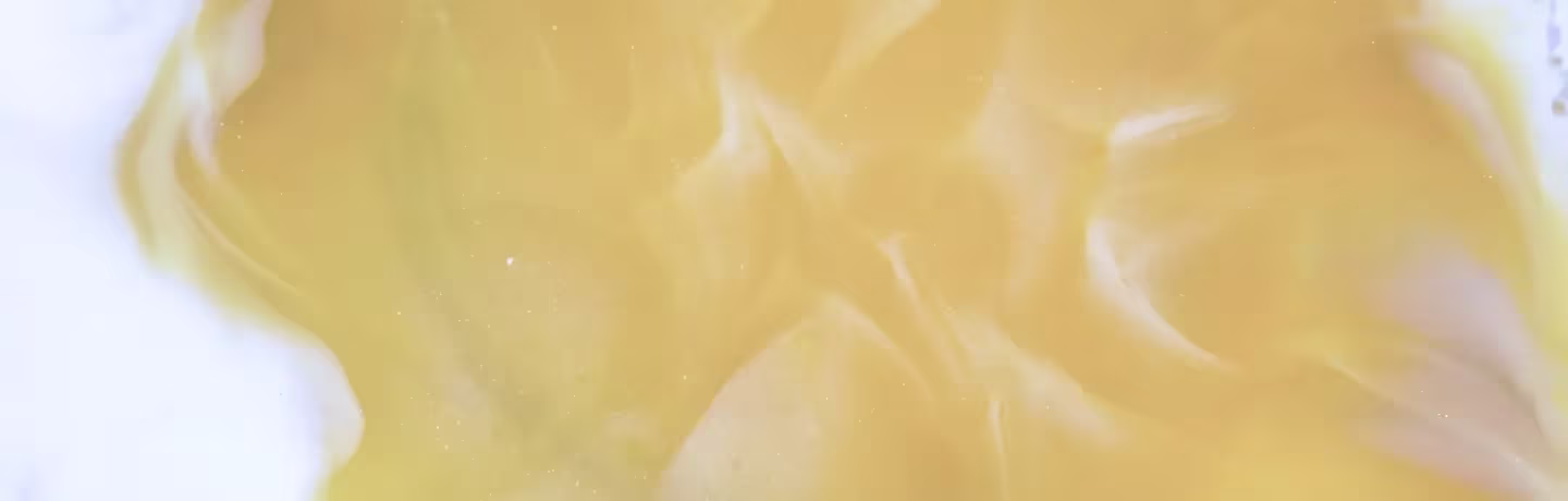 Vue rapprochée d'une surface lisse jaune clair avec un motif ondulé doux et des nuances subtiles qui ressemblent à une texture crémeuse ou marbrée.