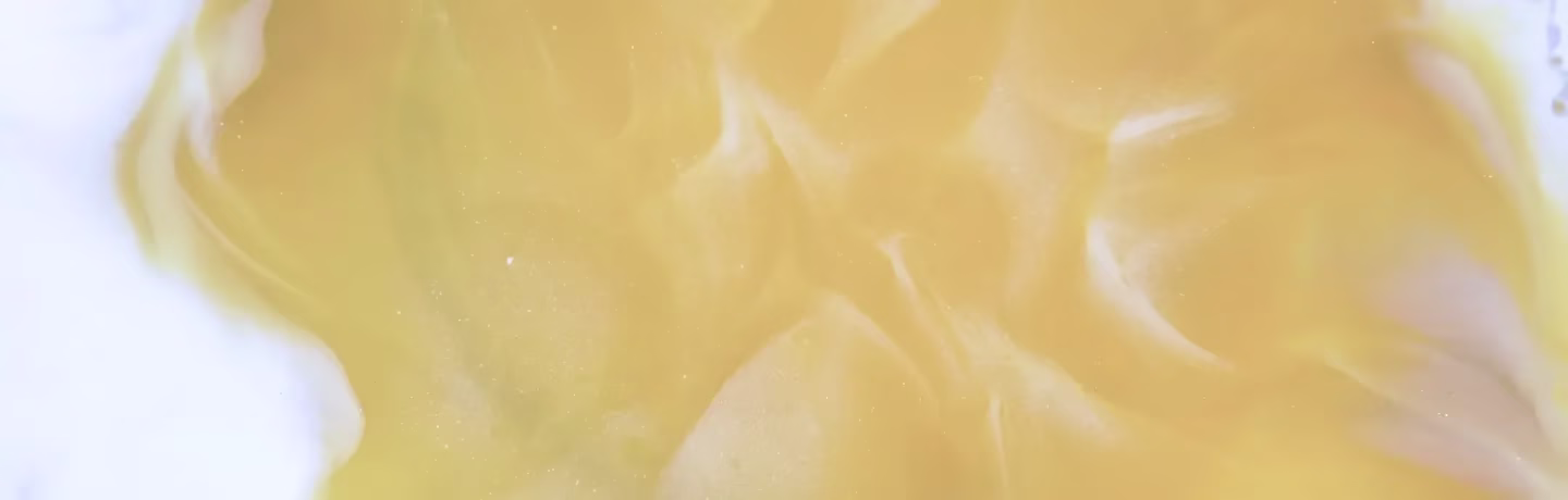 Close-up view of a smooth light yellow surface with a soft wavy pattern and subtle shading that resembles a creamy or marble-like texture.