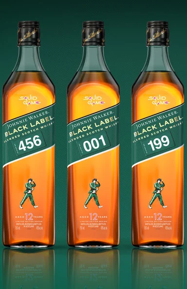 Three bottles of Johnnie Walker Black Label with custom labels featuring Squid Game designs. Each bottle is marked with a different number: 456, 001, and 199, against a green background.