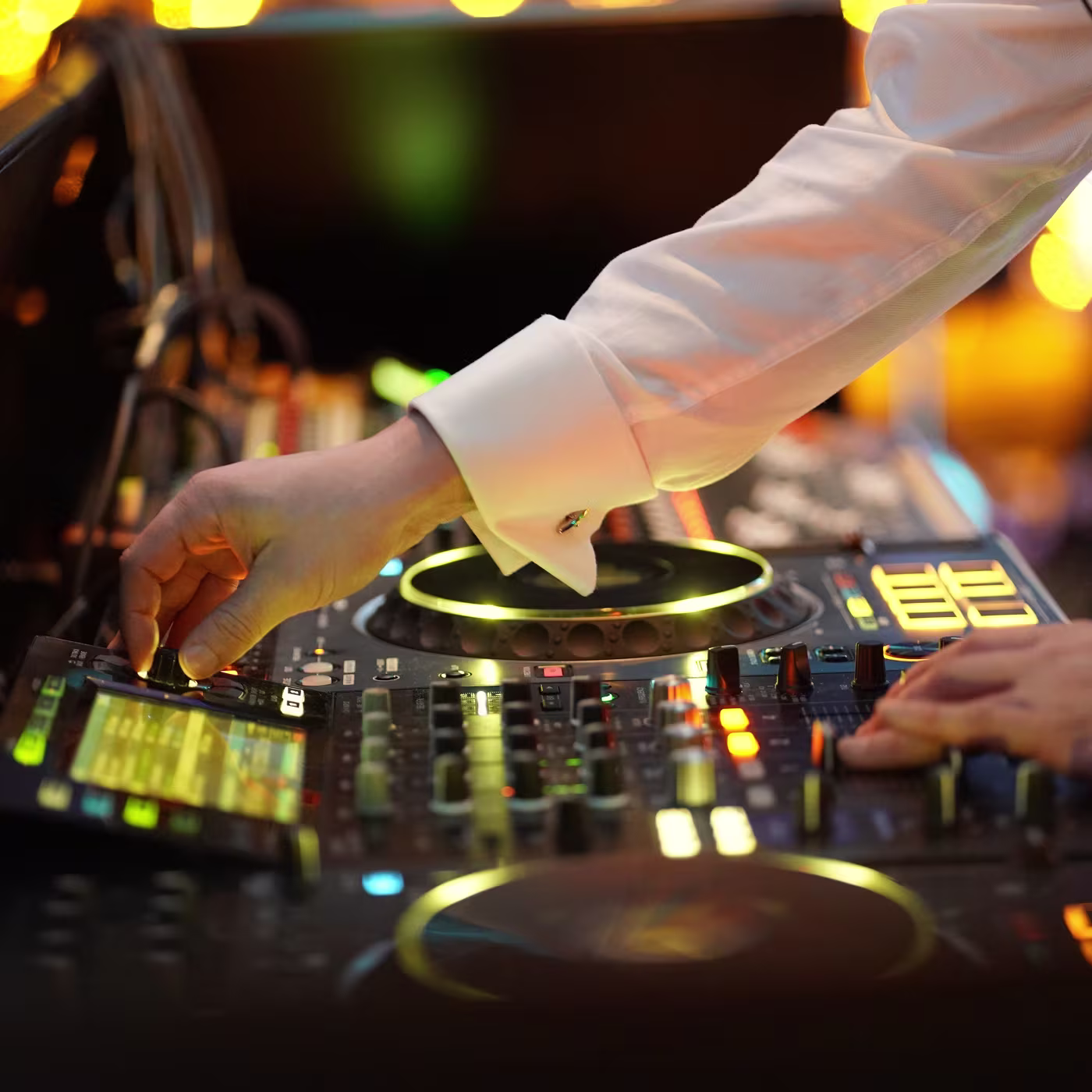 A person in a white shirt adjusts controls on a DJ mixer with glowing lights.