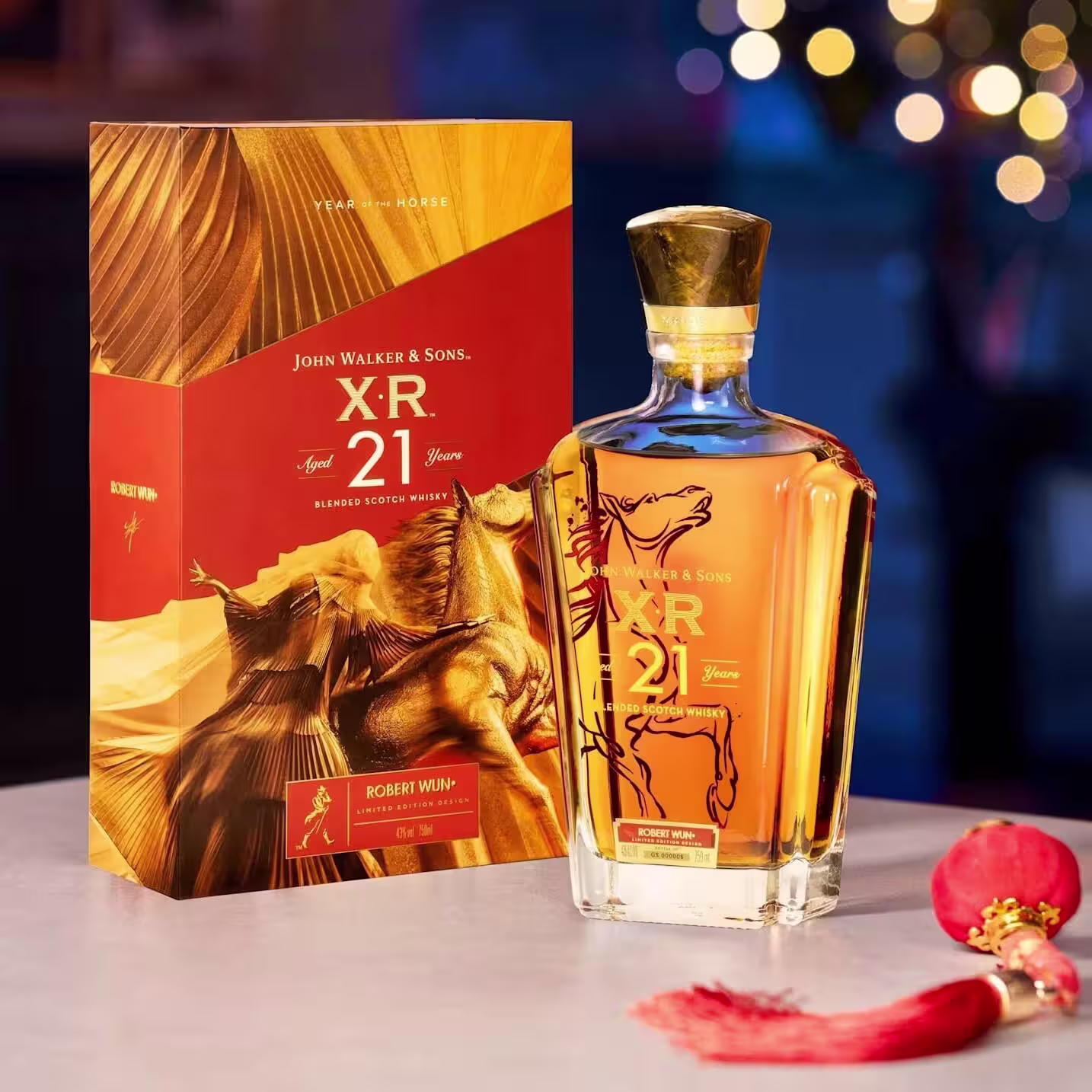 一瓶尊尼獲加 XR 21 年調和蘇格蘭威士忌,擺放在飾有駿馬圖案的金色盒子旁邊,旁邊還有節日裝飾品。